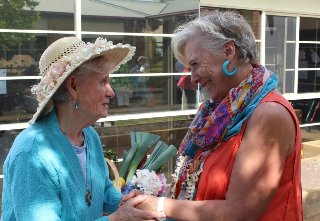 A senior lady holding hands with Maggie Beer
