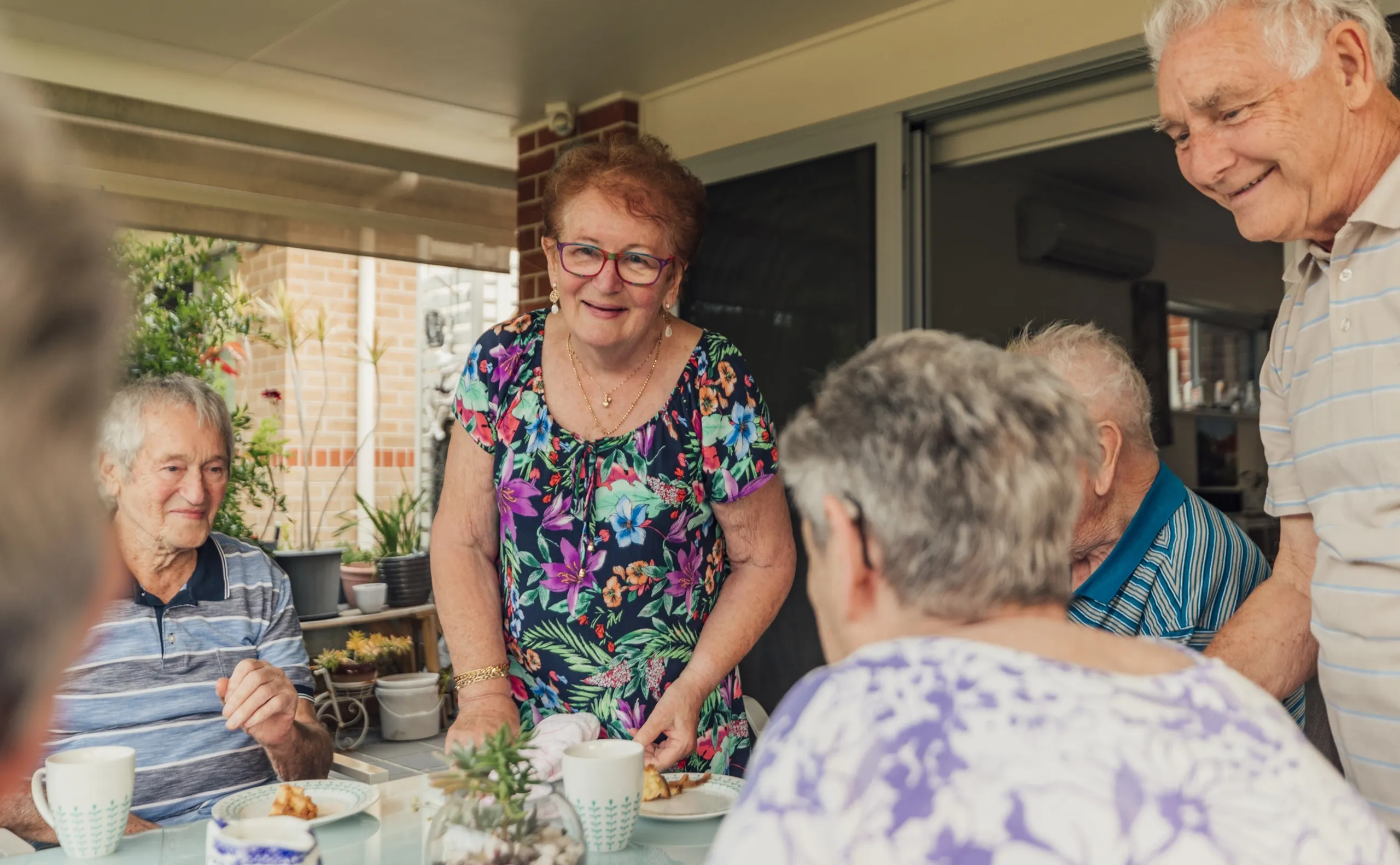 A group of senior friends and family all sitting at the table having lunch and chatting with each other.